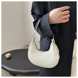 Close-up of white woven crescent moon shoulder bag with detailed texture and leather strap