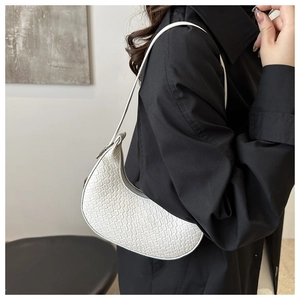 White woven hobo shoulder bag styled with a black trench coat for a chic contrast