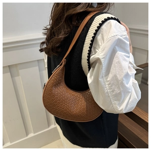 Brown leather hobo bag with woven texture worn by a model in a minimal style setting
