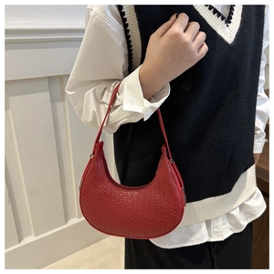 Detail of red crescent shoulder bag featuring premium woven texture and sleek zipper