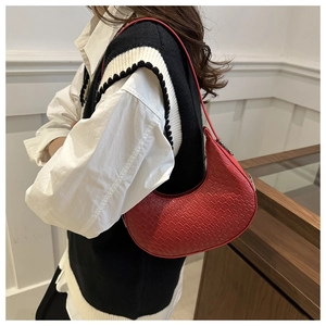 Detail of red croc-embossed crescent underarm bag worn with casual outfit