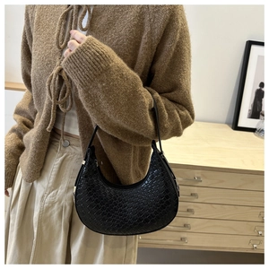 Detail of black woven texture and crescent shape on a French-style minimalist underarm bag
