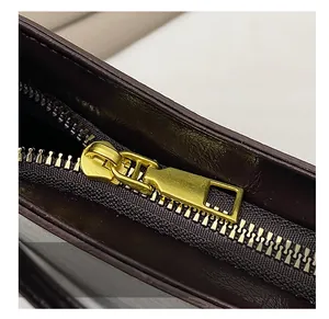 Detail showing smooth gold metal zipper and stitching on the burgundy crescent bag