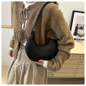 Detail of black woven crescent shoulder bag showing fine texture and sleek strap design