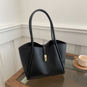 Borsa tote in pelle opaca nera con fibbia in metallo dorato su un tavolo in legno