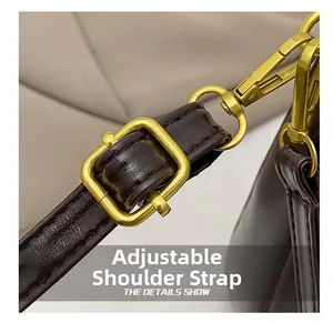 Detail view of the adjustable shoulder strap with vintage gold buckle on a brown crescent bag