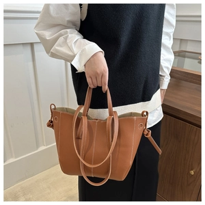 Détail d'un sac cabas caramel avec coutures contrastées et texture cuir grainé
