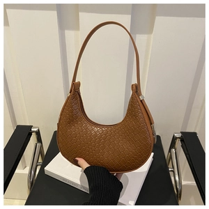 Detail of a brown woven crescent shoulder bag with leather texture and silver buckles
