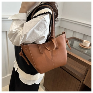 Detail of a brown lychee pattern tote bag with contrast white stitching and knot decor