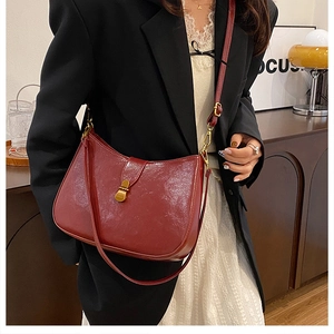 Detail of dark red leather crescent bag with gold buckle on a stylish model