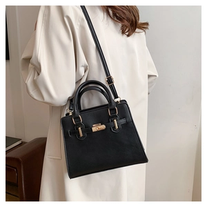 Detail of a chic black matte handbag featuring elegant gold twist lock and a slim strap