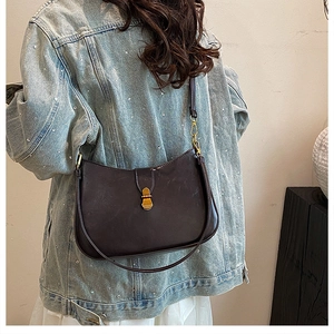 Detail showing a retro dark brown half-moon shoulder bag with a vintage gold buckle