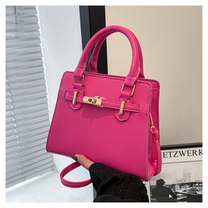 Close-up of bright pink leather handbag with gold twist lock and adjustable strap