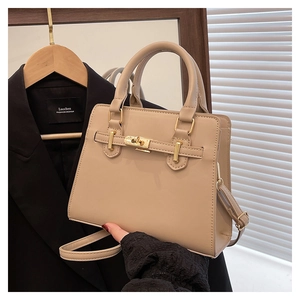 Detail of minimalist beige leather handbag featuring gold metal clasp and top handle