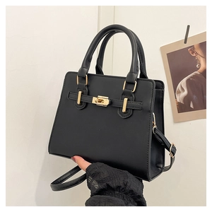 Detailed view of black minimalist Kelly handbag with golden buckle and sleek handles