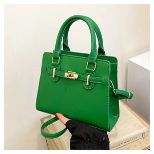 Detail of emerald green leather handbag featuring golden twist lock and lychee texture