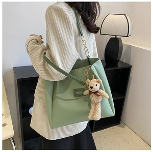 Detail of sage green tote bag with golden metal chain and cute teddy bear charm