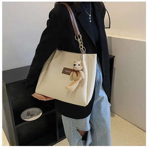 Detail of off-white tote bag featuring a leather fashion tag and a cute bear charm