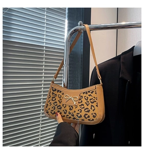 Close-up of leopard print shoulder bag with golden bow hardware and faux leather trim