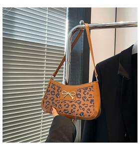 Close-up of leopard print underarm bag with gold bow buckle and elegant faux leather texture