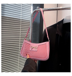 Detailed view of pink faux crocodile texture bag with a golden bow metal buckle