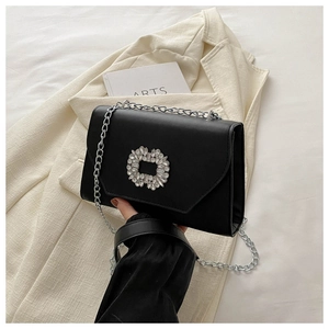 Close-up of black leather crossbody bag with a sparkling rhinestone buckle and silver chain