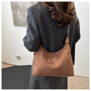 Brown suede hobo bag with silver chain strap shown on a gray tweed jacket outfit