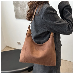 Detail view of large dark brown suede hobo bag with leather strap on shoulder