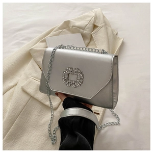Close-up of a silver chain bag with a sparkling rhinestone buckle and metallic finish