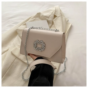 Detail of light beige chain bag with sparkling rhinestone buckle on a blazer