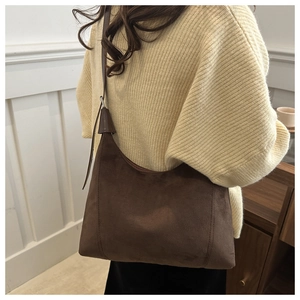 Detailed view of deep brown matte leather tote bag worn as a stylish underarm shoulder bag