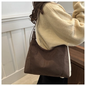 Detail of dark brown suede hobo bag worn by model, showing soft texture and stitching