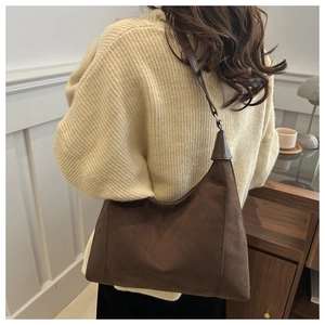 Detail of soft dark brown suede half-moon shoulder bag on model for daily casual wear