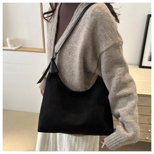 Detail of minimalist black hobo bag with matte texture and adjustable strap on a model