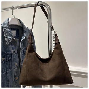 Close-up of brown suede hobo bag with silver chain detail on a denim background