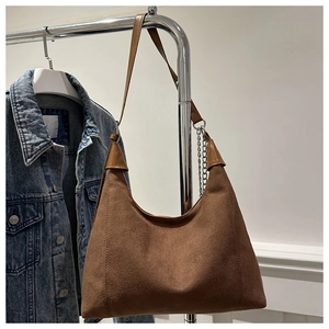 Detail of brown suede shoulder bag with silver chain accessory on a metal hanger