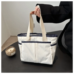 Detail of corduroy tote bag featuring multi-pocket design and navy blue ribbon trim