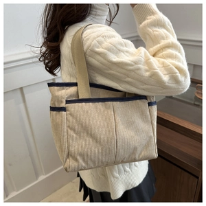 Detail of corduroy tote bag with multiple pockets and contrasting navy blue ribbon edge