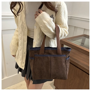 Detail of corduroy tote bag showing brown ribbed texture and blue contrast piping detail