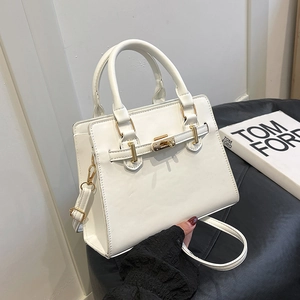 Minimalist white leather handbag with gold twist lock and adjustable shoulder strap