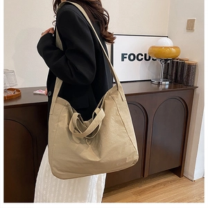 Detailed shot of large beige canvas tote bag with long shoulder straps and double handles