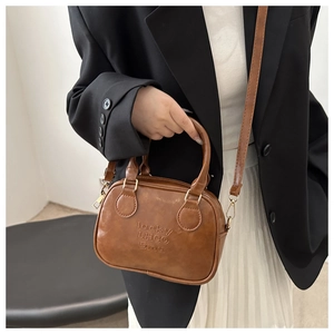 Detail of brown faux leather handbag showing embossed texture and gold hardware details