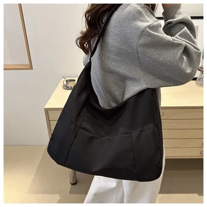 Detail of black waterproof nylon tote bag with decorative stitching on shoulder strap