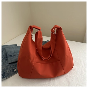 Close-up of rust red nylon tote bag featuring adjustable wide straps and silver metal buckles