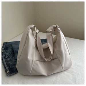 Detail showing high-quality texture and metal adjustment buckle on beige tote bag
