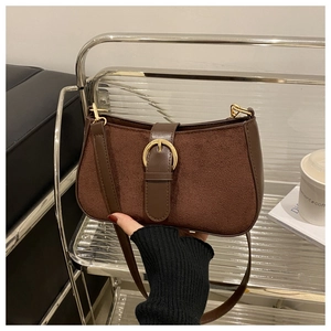 Detailed view of brown suede shoulder bag with golden round buckle and premium texture