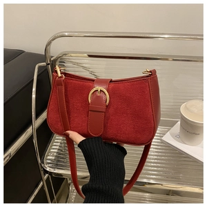 Detail of red vintage shoulder bag featuring a gold buckle and matte leather texture