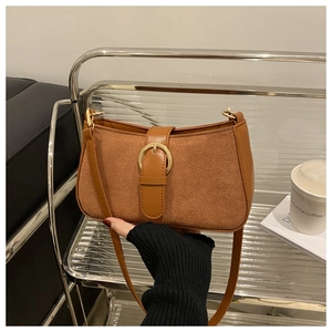 Detail of a brown leather shoulder bag featuring a gold buckle and textured suede panel