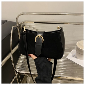 Detail of vintage matte black shoulder bag with gold buckle on a stylish leather sofa