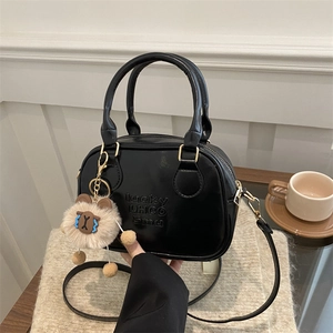 Petit sac carré noir brillant avec relief et charm ours sur un tissu en maille beige